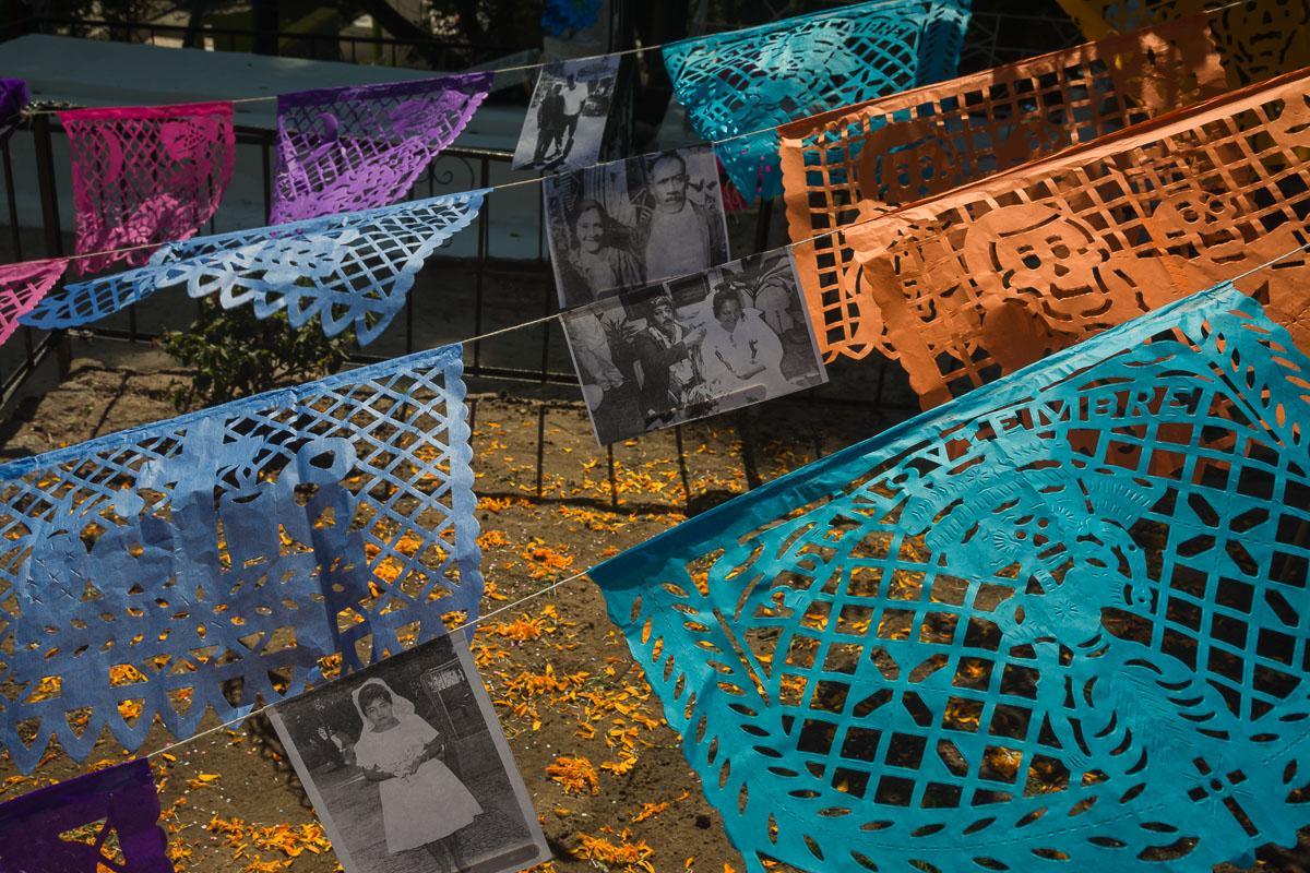 Papel picado, interspersed with photocopies of family photos, hangs over a tomb in the graveyard in Chapala, Jalisco, Mexico.