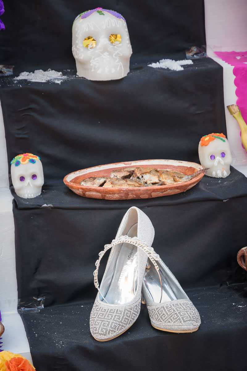 Shoes sit on an altar below an offering of a plate of fried fish at an altar in Chapala, Jalisco, Mexico.