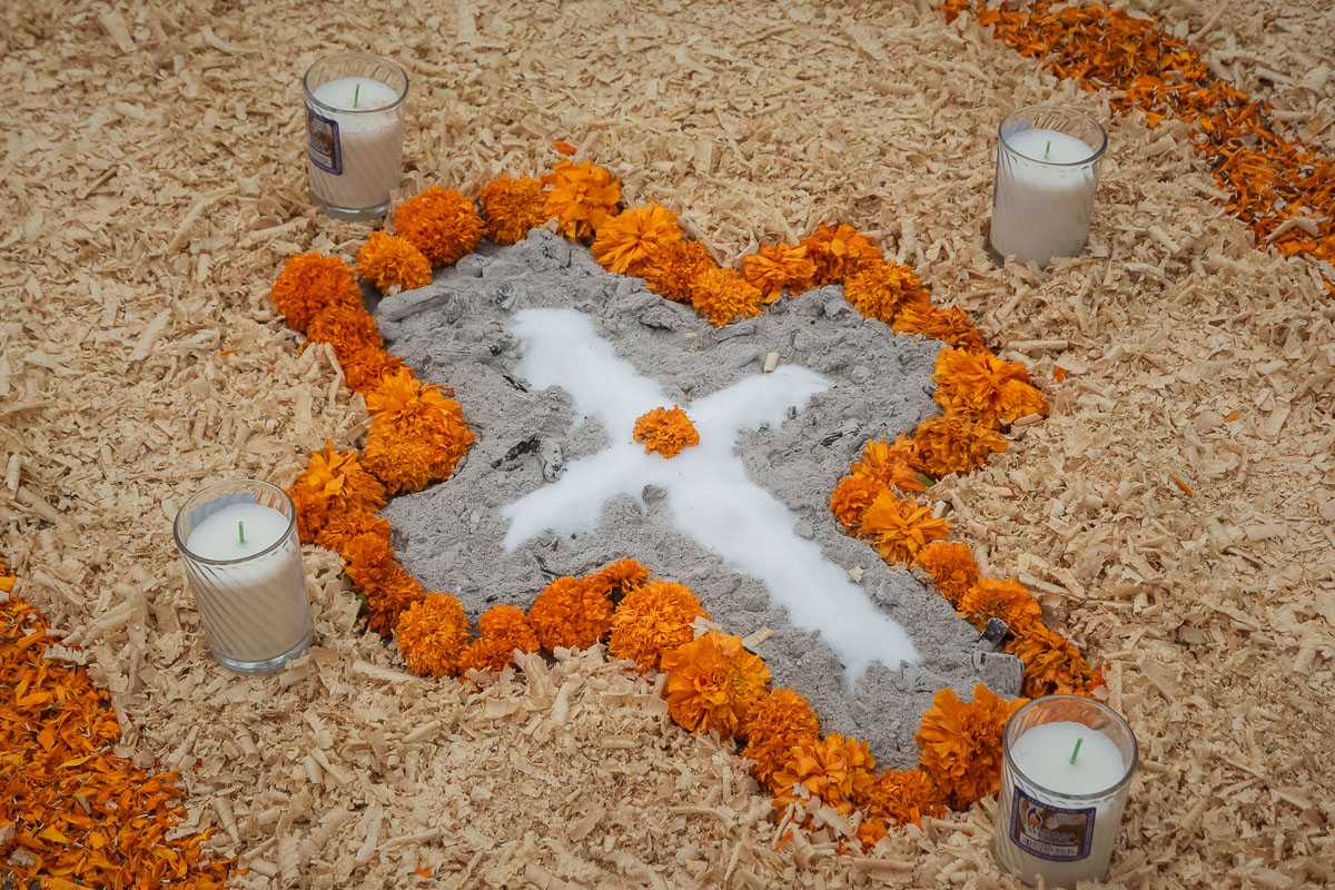 Salt forms the shape of a cross, outlined with ash and marigolds.