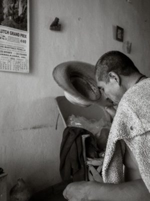Ismael Sánchez kisses the brim of his hat while saying a prayer after getting home, Ajijic, Jalisco, Mexico.