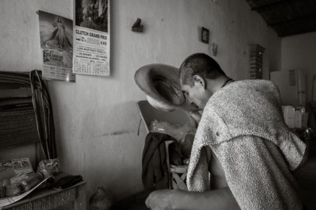 Ismael Sánchez kisses the brim of his hat while saying a prayer after getting home, Ajijic, Jalisco, Mexico.