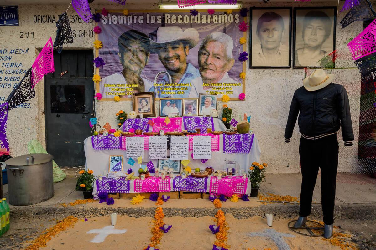 The Day of the Dead altar is built to welcome the dead back for their overnight journey to the living. Families leave offerings such as favorite foods or alcohol, as well as practical comforts such as soap and water, and clothes. For this altar, the family has dressed a mannequin with the deceased clothes and sombrero.