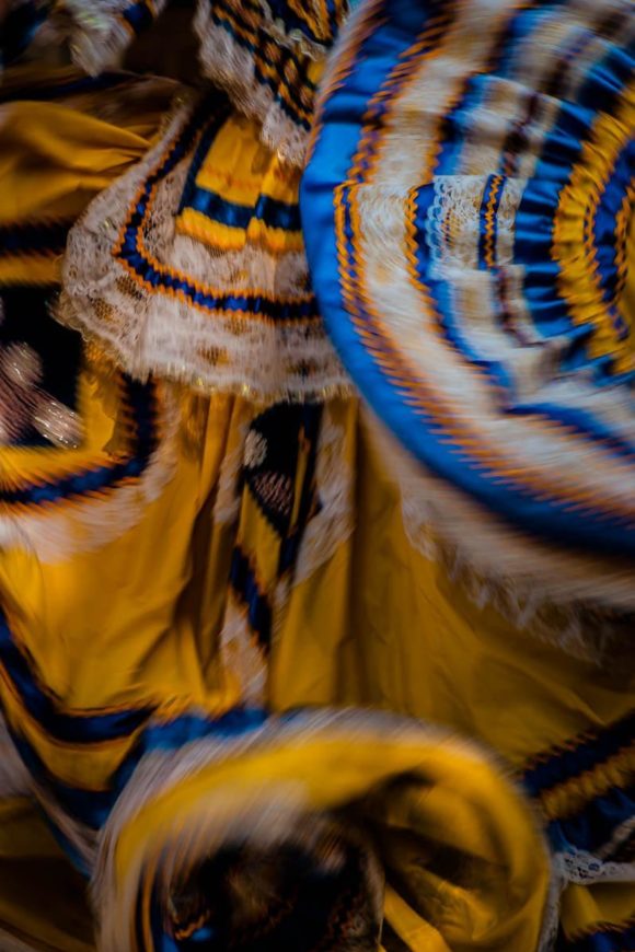 The dress of a Mexican ballet folklórico dancer blurs together during a performance in Jalisco, Mexico. Mexico has dozens of regional folk dances which have survived since their pre-Hispanic origin and today they're performed by dedicated dancers who are conscious of preserving the traditions which are in danger of being lost to modernity. The dress in this photo is a style typical from the region of Jalisco.
