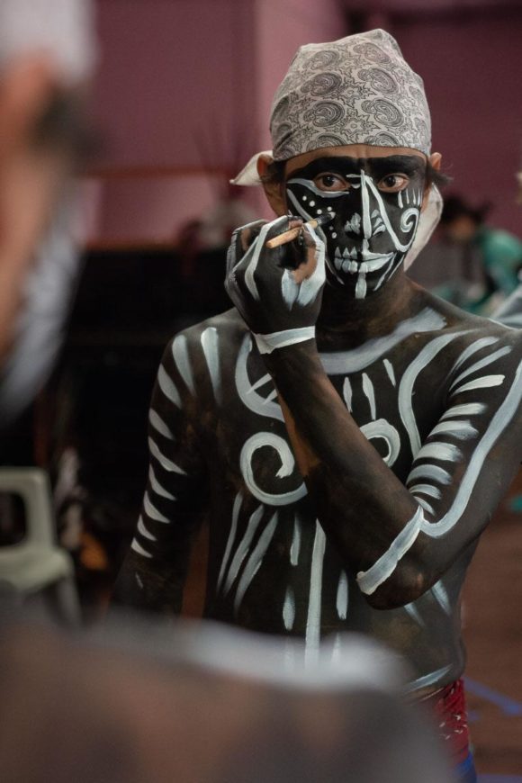 Sergio Hernández puts on his own face and body paint before a performance of a children's play. Sergio and other dancers were part of a program which introduced Aztec dance to young kids.