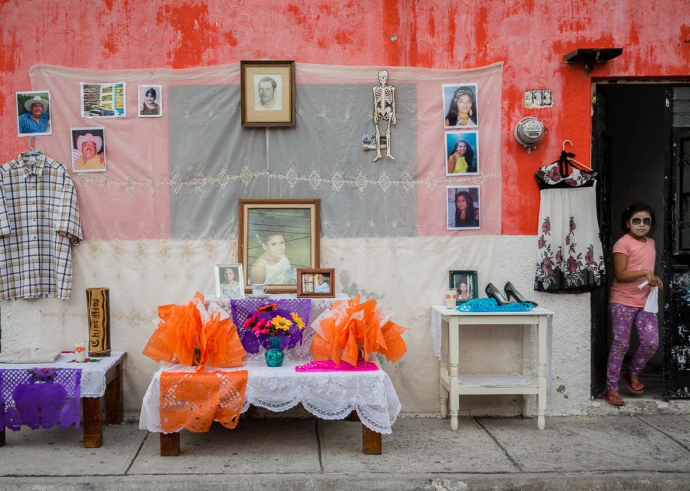 A girl with catrina face paint exits a house with an altar on the Day of the Dead in Chapala, Jalisco.