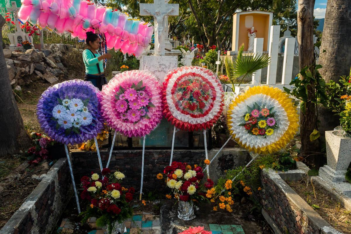 A woman selling cotton candy in the Chapala, Jalisco, graveyard walks by a tomb decorated with coronas on the Day of the Dead