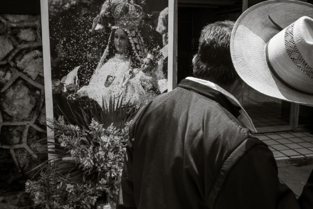 Man lifting his hat while passing image of La Virgen de la Merced in San Cristóbal de las Casas