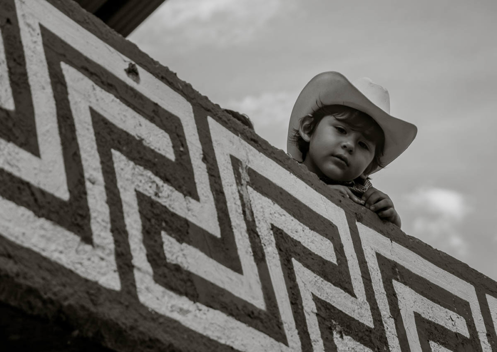 A little cowboy watches the events unfold in the town bullring.