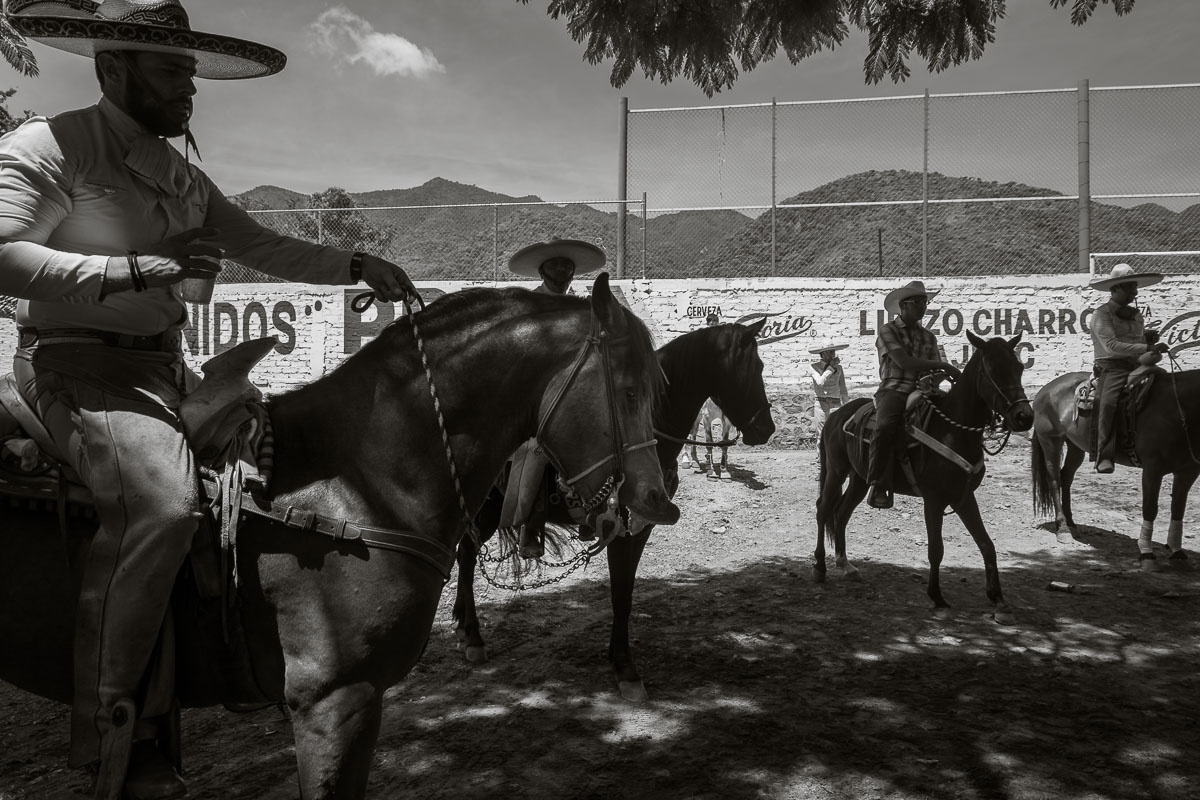 Cowboys on their horses drink and talk before the day's events at the bullring start.