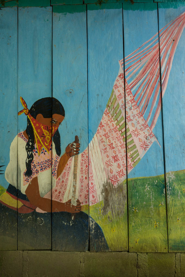 Painting of a woman weaving a rug.