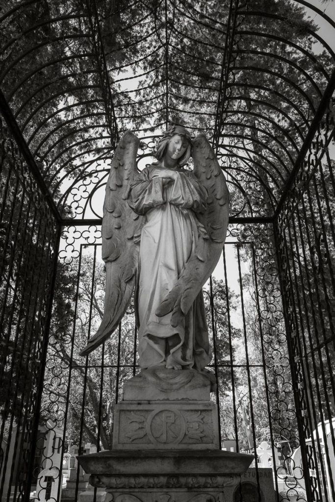 A statue of a stone angel inside a cage in the Panteón Municipal in Morelia, Michocacán.