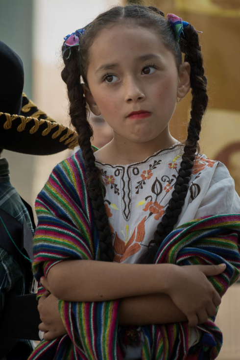 An adelita girl, looking annoyed at something, waits for the parade to start on Revolution Day in Ajijic, Mexico.