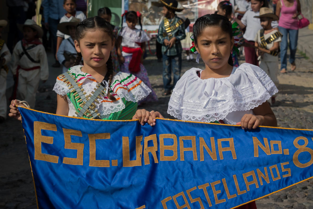Adelitas holding a banner which represents their school during the Revolution Day parade in Ajijic, Mexico.