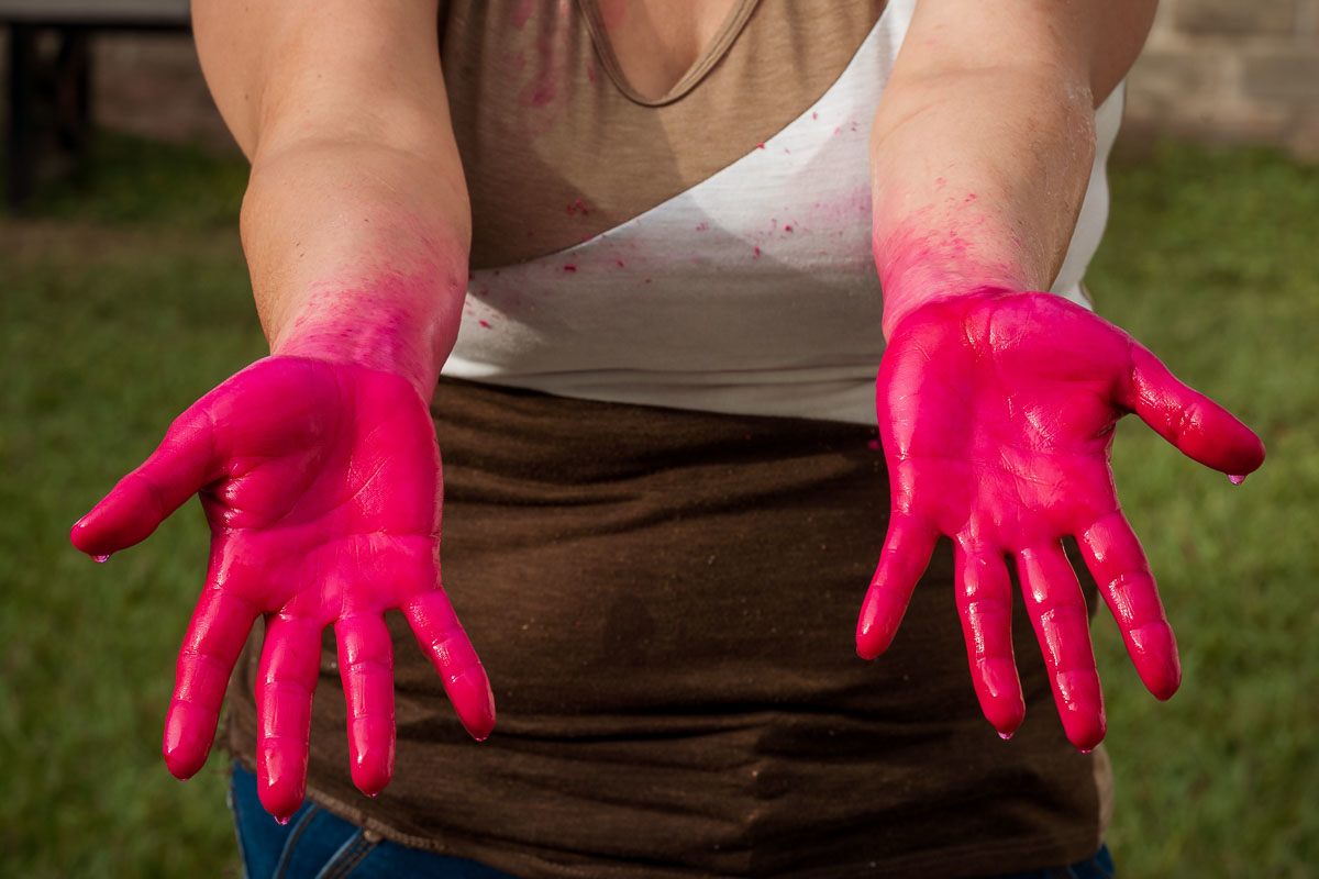 A person's hands stained with magenta dye.