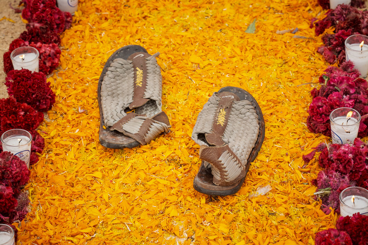 A pair of huarache sandals sits on a carpet of marigold petals.