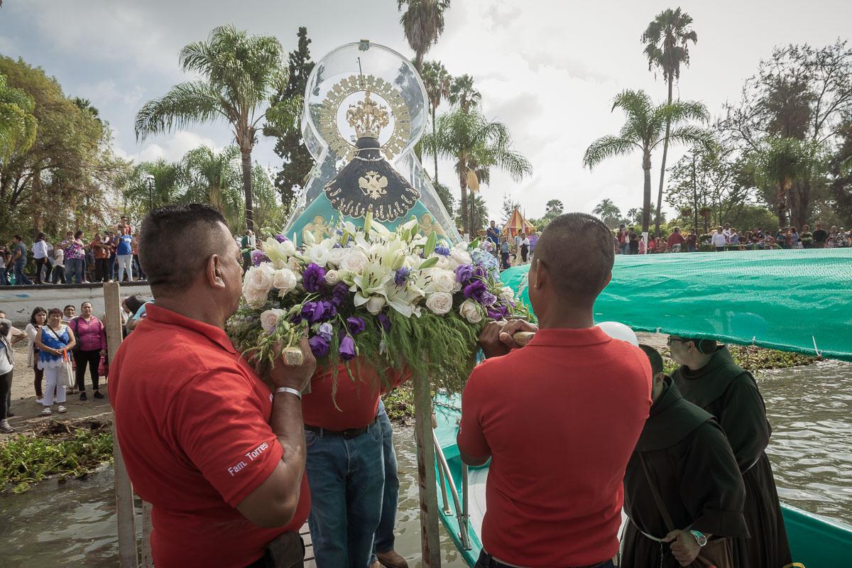 The virgin arrives at the dock and to get placed securely in one of the boats. The wooden icon is actually one of a few existing copies of the Virgin. After an accident in the last decade or so, the original virgin no longer strays from the basilica in Zapopan where she resides.