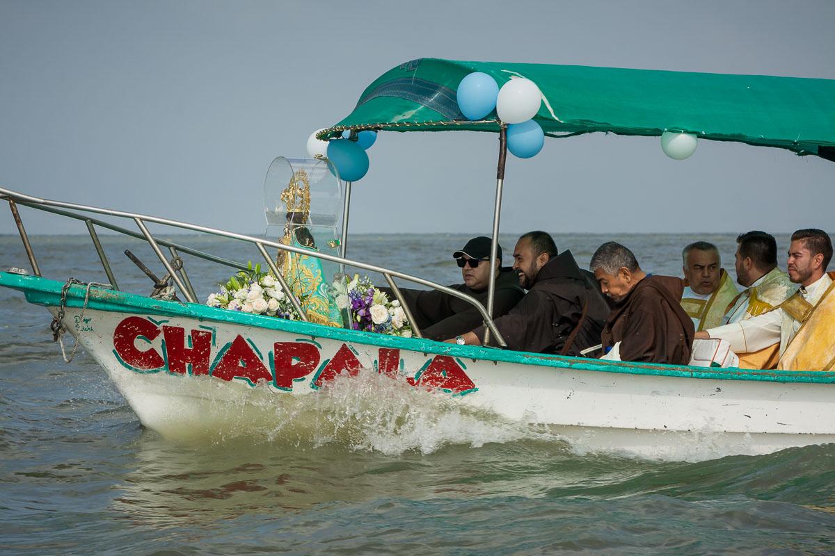 Clergy members ride with the virgin and help ensure that she doesn't topple over on the way to the island.